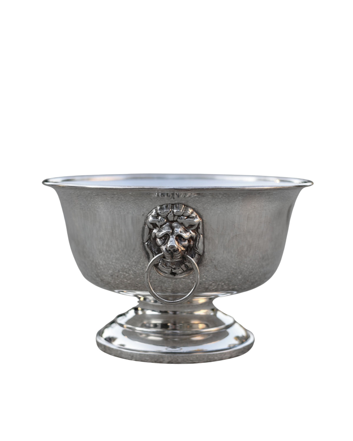 A vintage silver pedestal bowl with a lion head ring pull handle, isolated on a white background.